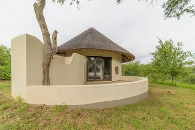 a small house with a thatched roof in a field at Lengau Lodge in Grietjie Nature Reserve