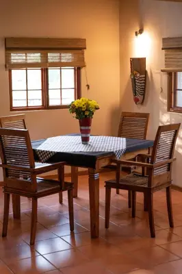 a dining room table with two chairs and a vase with flowers at Blyde River Wilderness Lodge in Hoedspruit