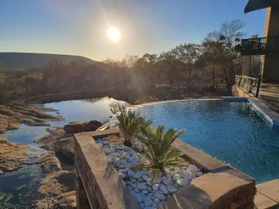 a swimming pool with a bridge over a river at Tholo Private Game Lodge in Bela-Bela