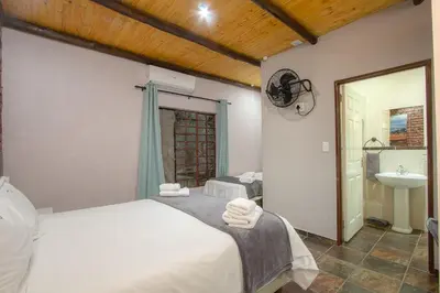 a bedroom with a white bed and a sink at Kruger Wild Dog Inn in Marloth Park