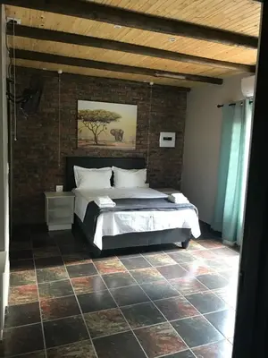 a bedroom with a bed and a brick wall at Kruger Wild Dog Inn in Marloth Park