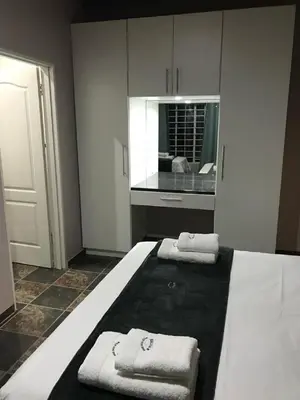 a white bedroom with two towels on a bed at Kruger Wild Dog Inn in Marloth Park