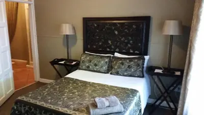 a bedroom with a large bed with two lamps at The Yardt Guest House in Trichardt