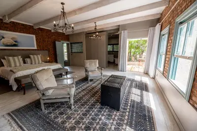 a bedroom with a bed and a table and chairs at Migdash Guesthouse in Hartbeespoort