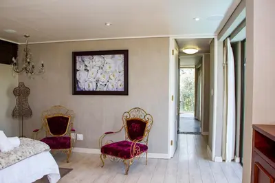 a bedroom with two chairs and a bed at Migdash Guesthouse in Hartbeespoort