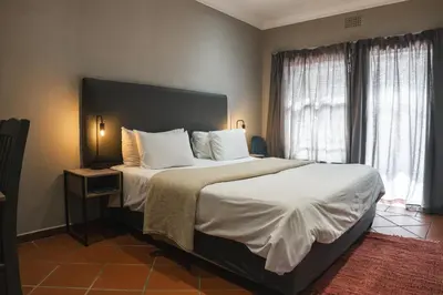 a bedroom with a large bed with white pillows at The Wild Peach - Menlyn in Pretoria