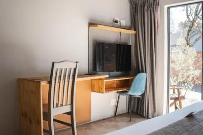 a room with a desk with a television and a chair at The Wild Peach - Menlyn in Pretoria
