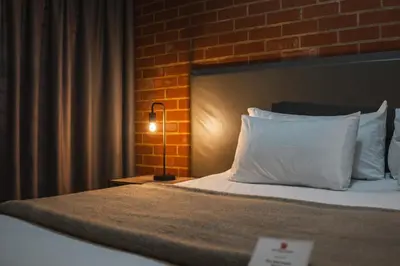 a bedroom with a bed with a brick wall at The Wild Peach - Menlyn in Pretoria