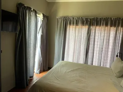 a bedroom with a bed and two windows at The Wild Peach - Menlyn in Pretoria