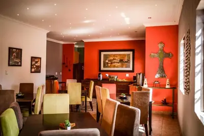 a dining room with orange walls and a table and chairs at Guesthouse Serenity in Hartbeespoort