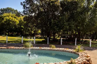 a swimming pool with a fountain in a park at Guesthouse Serenity in Hartbeespoort