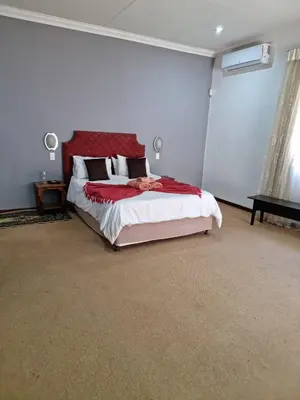 a bedroom with a large bed with a red headboard at Guesthouse Serenity in Hartbeespoort