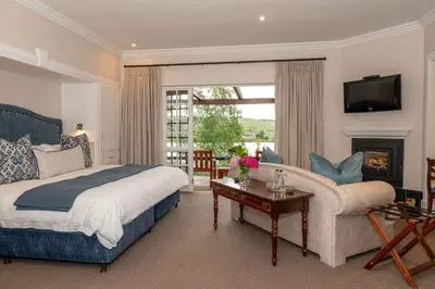 a bedroom with a bed and a couch and a fireplace at Walkersons Hotel & Spa in Dullstroom
