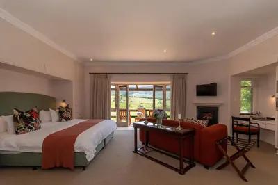 a bedroom with a bed and a desk and a chair at Walkersons Hotel & Spa in Dullstroom