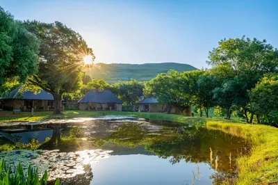 a sunset over a pond in front of a lodge at Walkersons Hotel & Spa in Dullstroom