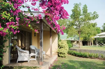 a porch with two chairs and pink flowers at Perry's Bridge Hollow Boutique Hotel in Hazyview