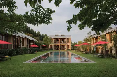 a pool in front of a building with red umbrellas at Casterbridge Hollow Boutique Hotel in White River