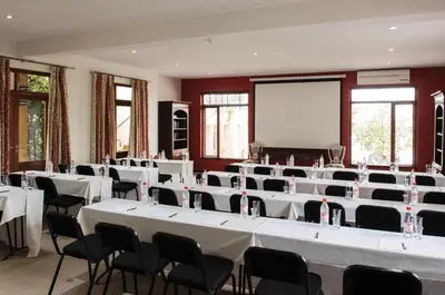 a room with white tables and chairs and a screen at Casterbridge Hollow Boutique Hotel in White River