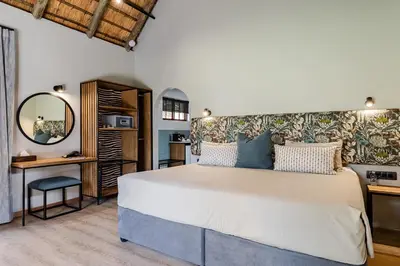 a bedroom with a large bed and a mirror at Hippo Hollow Country Estate in Hazyview