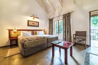 a bedroom with a bed and a table and a chair at Hippo Hollow Country Estate in Hazyview