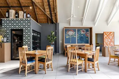a dining room with wooden tables and chairs at Hippo Hollow Country Estate in Hazyview
