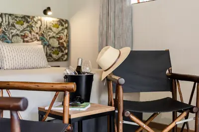 a room with a bed and a chair and a hat at Hippo Hollow Country Estate in Hazyview