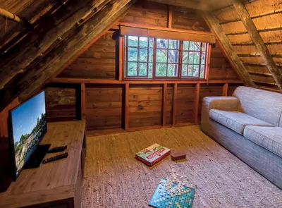 a living room with a couch and a tv in a cabin at Hippo Hollow Country Estate in Hazyview