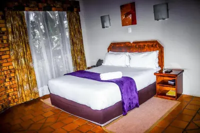 a bedroom with a bed with a purple blanket on it at Vido Lodge and Conference Centre in Polokwane