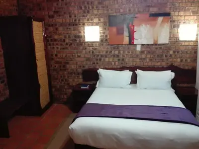 a large bed in a room with a brick wall at Vido Lodge and Conference Centre in Polokwane