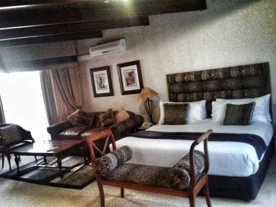 a bedroom with a bed and a couch and a table at Vido Lodge and Conference Centre in Polokwane