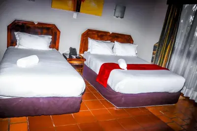 two beds in a hotel room with a red blanket at Vido Lodge and Conference Centre in Polokwane