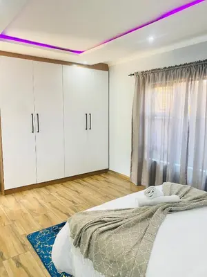 a bedroom with white cabinets and a large bed at Airport Imperial Guest House in Kempton Park