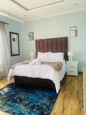 a bedroom with a large bed with a wooden headboard at Airport Imperial Guest House in Kempton Park