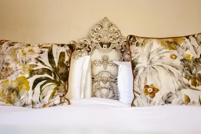 a white bed with floral pillows on top of it at Town and Country Mpumalanga in Middelburg