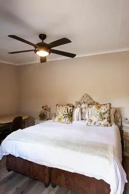 a bedroom with a bed with a ceiling fan at Town and Country Mpumalanga in Middelburg