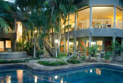 a house with a swimming pool and palm trees at Belvedere-on-River in Malelane