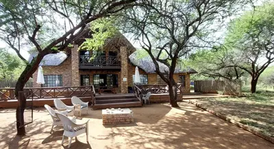 a patio with chairs and a bench in front of a house at Khumbula iAfrica 1 in Marloth Park