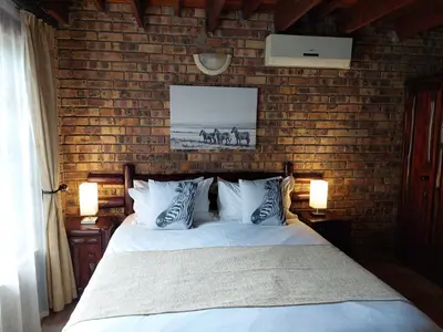 a bedroom with a bed and a brick wall at Khumbula iAfrica 1 in Marloth Park