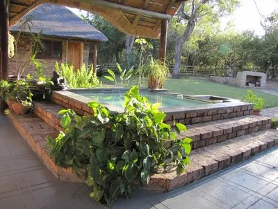 a swimming pool in a garden with plants at SERENITY Du Bois Lodge in Marloth Park