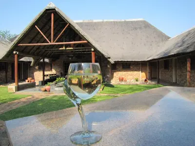 a wine glass sitting on a table in front of a building at SERENITY Du Bois Lodge in Marloth Park