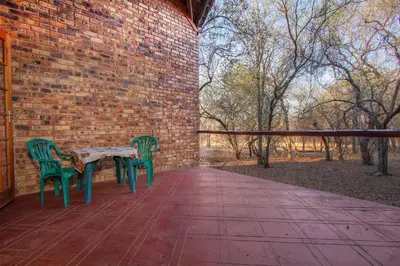 two green chairs and a table on a patio at SERENITY Du Bois Lodge in Marloth Park