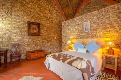 a bedroom with a bed and a brick wall at SERENITY Du Bois Lodge in Marloth Park
