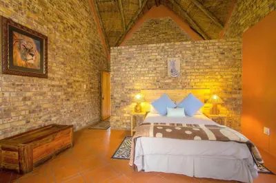 a bedroom with a bed and a brick wall at SERENITY Du Bois Lodge in Marloth Park