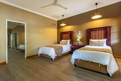 a bedroom with two beds and a mirror at Little Pilgrims Boutique Hotel in Hazyview