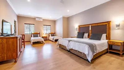 a bedroom with a large bed and a dresser and chair at Little Pilgrims Boutique Hotel in Hazyview