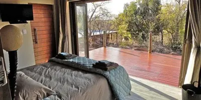 a bedroom with a bed and a large window at Feeskraal Lodge in Moheme