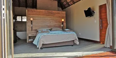 a bedroom with a large bed with a wooden headboard at Feeskraal Lodge in Moheme