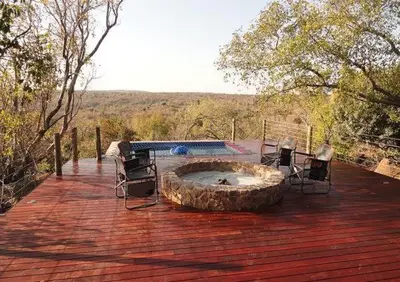 a wooden deck with chairs and a fire pit at Feeskraal Lodge in Moheme