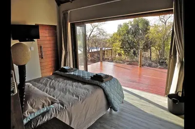 a bedroom with a bed and a large window at Feeskraal Lodge in Moheme