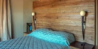 a bed in a bedroom with a wooden wall at Feeskraal Lodge in Moheme